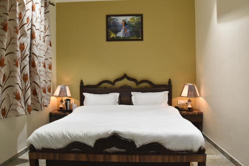 斋浦尔Jaipur Hotel New - Heritage Hotel的一间卧室配有一张带白色床单和两盏灯的床。