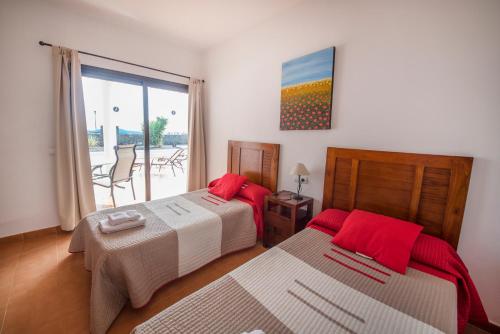 普拉亚布兰卡Villas Blancas的一间卧室配有两张带红色枕头的床