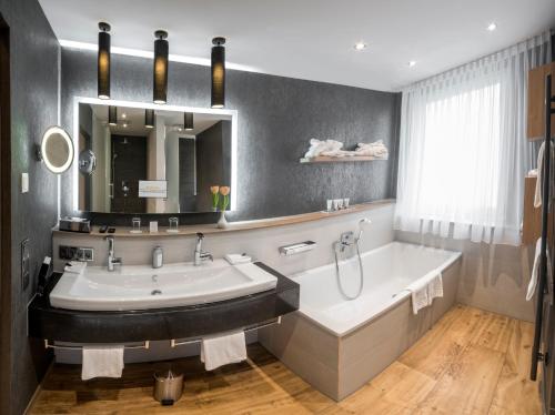 慕尼黑德瑞洛温酒店的带浴缸、水槽和镜子的浴室