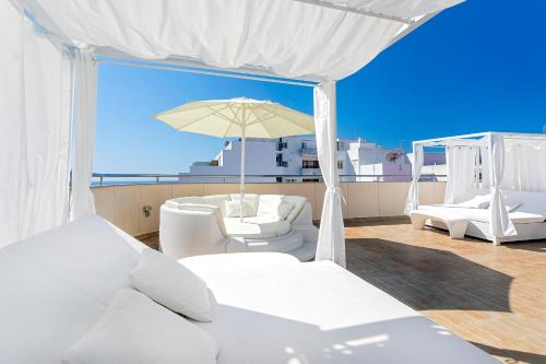 圣埃乌拉利亚杜克沙普拉亚公寓式酒店的阳台配有白色家具和雨伞。