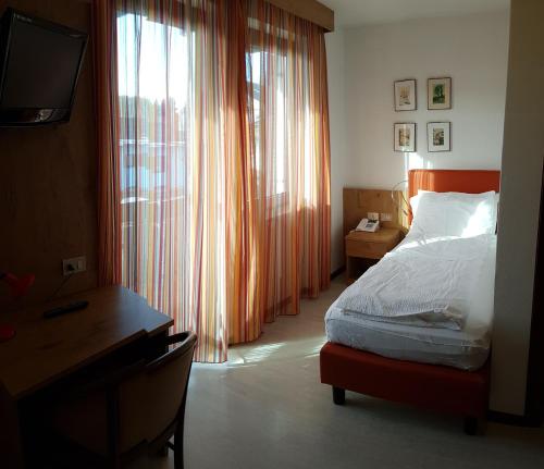 巴塞尔加·迪·皮纳奥林匹克酒店的一间卧室配有一张床、一张书桌和一个窗户。