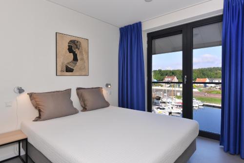 坎珀兰d'Ouwe Haven 10F的一间卧室配有一张带蓝色窗帘的床和一扇窗户