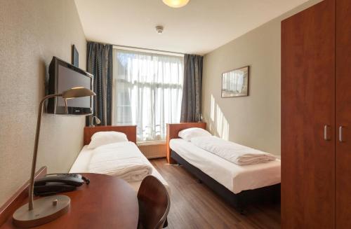 阿姆斯特丹A火车酒店的酒店客房设有两张床、一张书桌和一个窗户。
