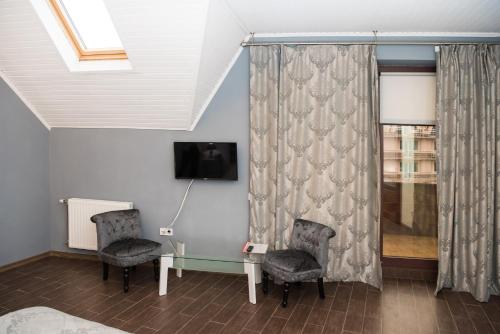 乌日霍罗德Hotel " BOUTIQUE "的一间设有两把椅子、一张桌子和一台电视的房间