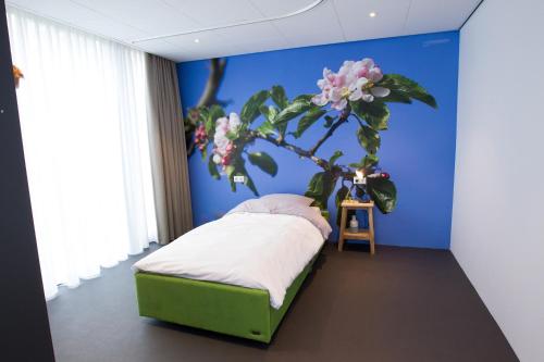 Heerdede rode beer (zeer rolstoelgeschikt)的卧室配有一张床铺,墙上挂着一棵树