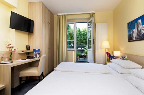杜塞尔多夫霍夫加登酒店的酒店客房设有两张床、一张书桌和一个窗户。