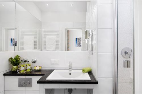 杜塞尔多夫霍夫加登酒店的白色的浴室设有水槽和淋浴。