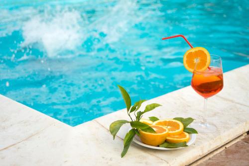 卡塔尼亚Sicily Country House & Beach的一杯橙汁在泳池旁