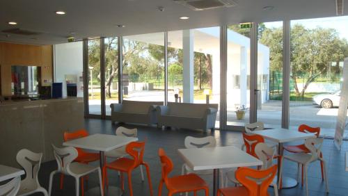 蒙塔吉尔Parque de Campismo Orbitur Montargil的一间设有橙色和白色桌椅的餐厅