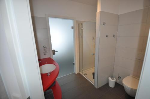 不来梅港不莱梅新港公寓的一间带红色卫生间和水槽的浴室