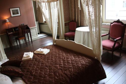 伊普尔La Porte Cochère的卧室配有一张床和一张桌子及椅子