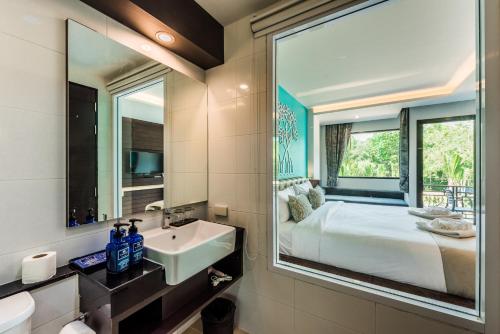 甲米镇甲米河畔酒店的一间带水槽的浴室和一张带镜子的床