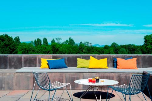 潘普洛纳Eurostars Pamplona的庭院配有两把椅子和一张带彩色枕头的桌子。