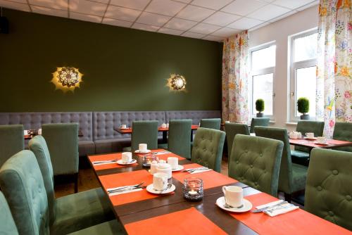 霍根海姆ACHAT Hotel Hockenheim的用餐室配有桌子和绿色椅子