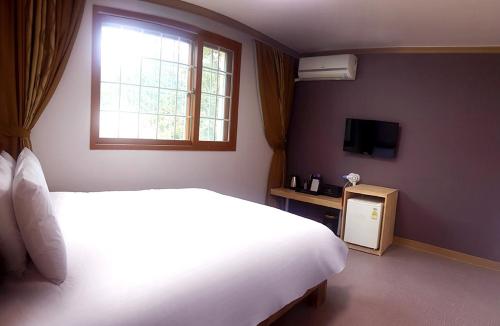 茂朱姆居度假屋的卧室设有一张白色大床和一扇窗户。