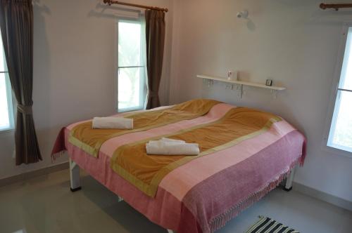 三百岭班汗里玛度假屋的一间卧室配有一张床,上面有两条毛巾
