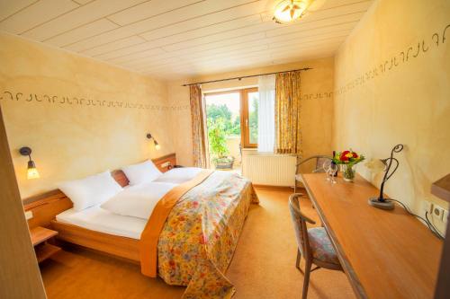 WindsbachLandgasthof Schwarz的酒店客房配有一张床、一张书桌和一张四柱床