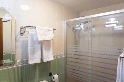 卡萨韦梅哈Pensión y apartamentos El Taxi的一间带玻璃淋浴间和毛巾的浴室