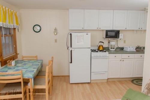 丹尼斯港Oceanside Condos的厨房配有白色冰箱和桌子