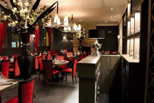 Aunay-sur-OdonLOGIS -Hotel & Restaurant de la Place的餐厅设有红色的桌椅和吊灯