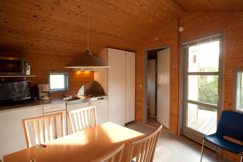 腓特烈港腓特烈诺德斯特德野营和别墅酒店的一间厨房和带木制天花板的用餐室