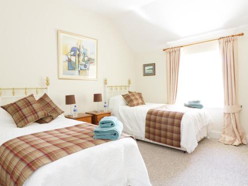 NewtyleBannatyne Lodge的一间卧室设有两张床和窗户。