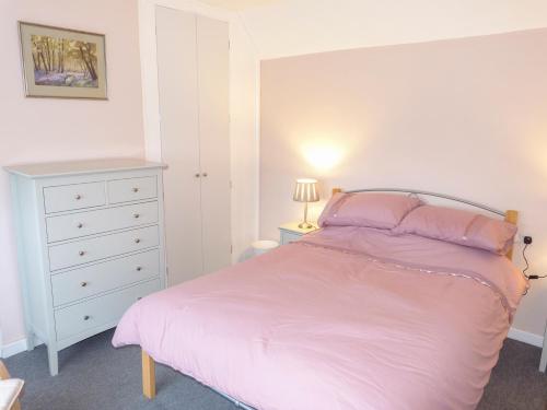 巴特尔Amelia Cottage的卧室配有粉红色的床和白色梳妆台