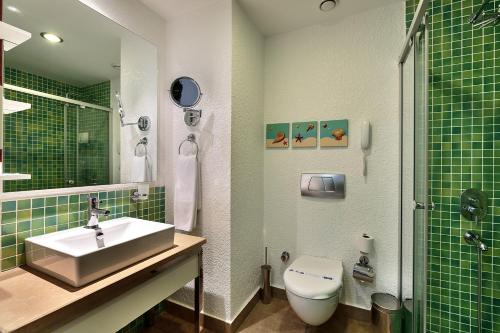 锡德苏尼斯埃夫伦海滩水疗度假酒店 的绿色瓷砖浴室设有水槽和卫生间
