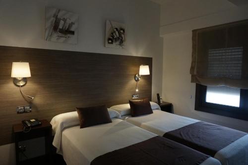 拉科鲁尼亚Suites Coruña的酒店客房设有两张床和窗户。