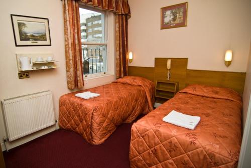 伦敦Alexandra Hotel的酒店客房设有两张床和窗户。