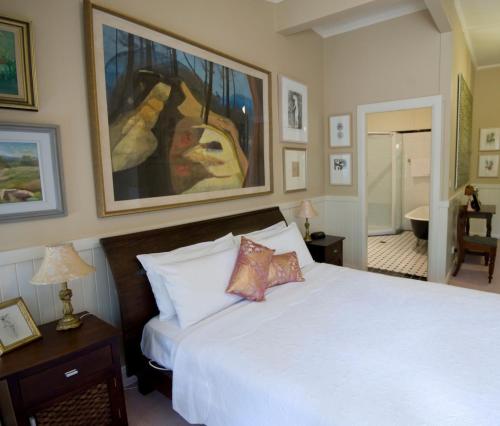 美德罗巴斯木屋旅馆及公寓的卧室配有白色的床和墙上的绘画作品