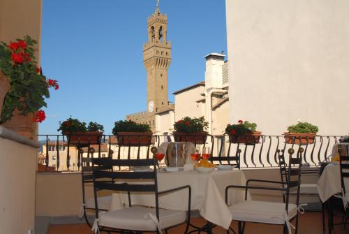 佛罗伦萨迪格里奥拉费酒店的一个带钟楼的阳台的桌椅
