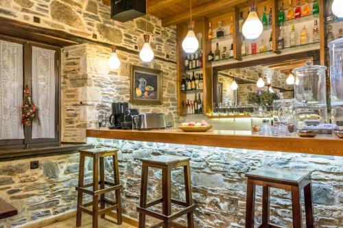 阿伊埃斯拉伦蒂欧斯Iliopetra Suites的石头墙上有两张凳子的酒吧