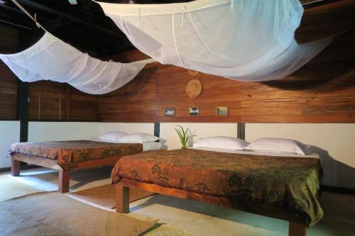 额布里Kipling's Bay Guest house的一间卧室设有两张床和一个带蚊帐的天花板。