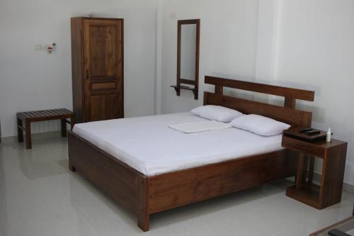 拉特纳普勒Gem Field Rest的一间卧室配有一张带两个枕头的木床