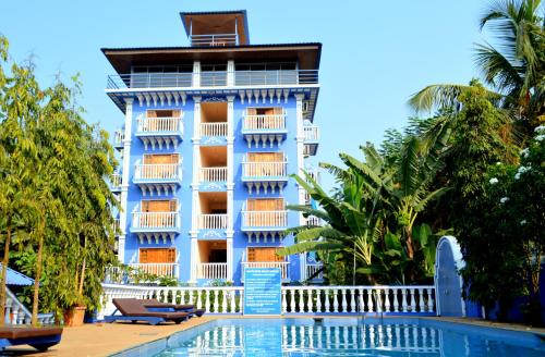 巴加五月花海滩度假酒店的蓝色的建筑,前面设有一个游泳池