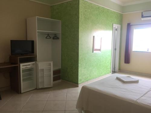 马卡帕美斯酒店的一间卧室设有床铺、电视和绿色墙壁。