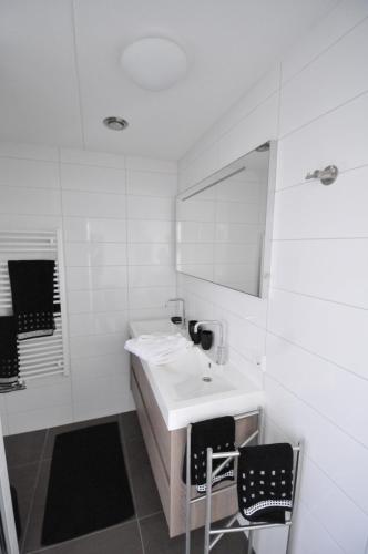 栋堡Roosjesweg 1a的白色的浴室设有水槽和两把椅子