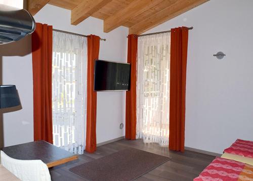 涅德劳Flatscher‘s的客厅设有两扇带橙色窗帘的窗户。