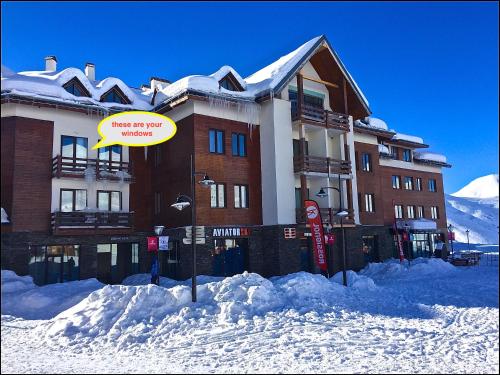 古多里Zen Apartments Gudauri的一座大建筑,在雪中标有标志