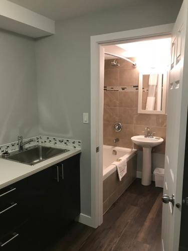 One Hundred Mile House94 Motel & RV Park的浴室配有盥洗盆、浴缸和盥洗盆。