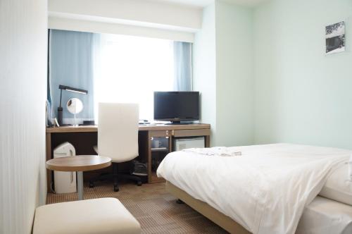 那霸冲绳县厅前大和ROYNET酒店的一间卧室配有一张床和一张书桌及电视