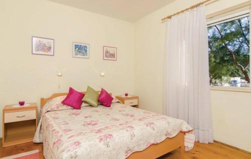 OkukljeOkuklje Holiday Home的一间卧室配有带粉红色枕头的床和窗户。