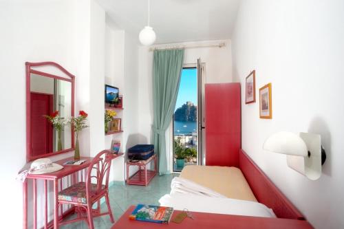 伊斯基亚乌丽赛酒店的一间卧室配有一张床、一张书桌和一个窗户。