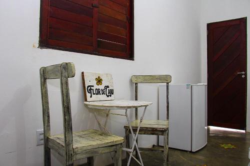 皮帕Hospedaria Flor de Caju的客房设有2把椅子、桌子和冰箱。