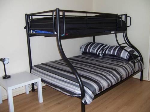 Port Hughes放松身心度假屋的一张黑色双层床,上面有条纹枕头