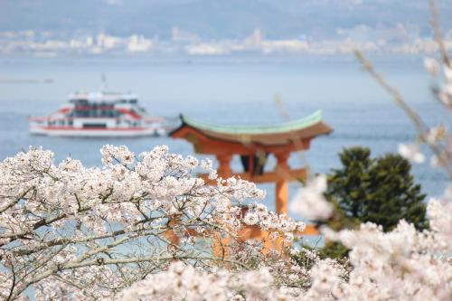 广岛广岛COCO旅馆（仅限女性）的一座宝塔和一条水中装有粉红色花的船