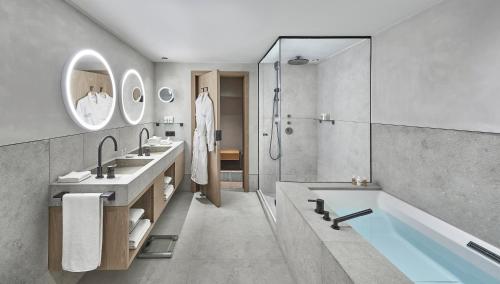 基茨比厄尔Hotel Weisses Roessl的浴室配有2个盥洗盆、浴缸和淋浴。