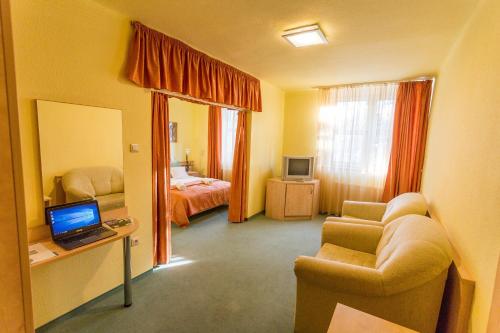 绍尔戈陶尔扬Salgó Hotel的客房设有一间卧室,配有一张床和一张带笔记本电脑的书桌