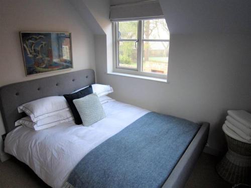 奥福德Crown Cottage - Prime Orford Location的一间卧室配有一张带白色床单的床和一扇窗户。